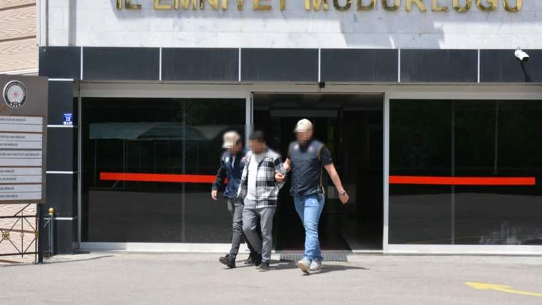 İl Emniyet Müdürlüğü yazılı binanın girişinden iki görevlinin eşlik ettiği bir kişi çıkarılıyor.