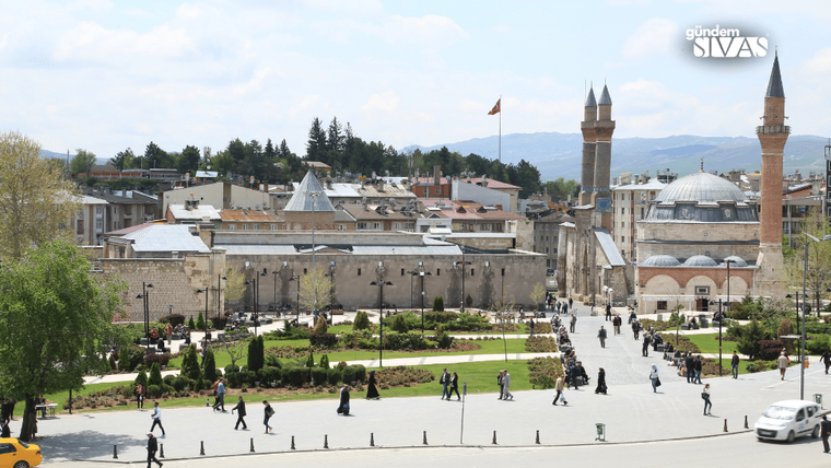 Sivas'ta bir meydan, etrafında insanlar yürüyüş yapıyor, ağaçlar ve yeşil alanlar var.