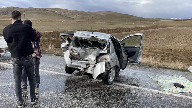 Yolda hasar görmüş bir otomobil, kapıları açık şekilde duruyor; arka kısmı ezilmiş.