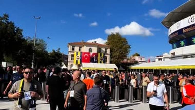 Stadyum girişinde bekleyen kalabalık arasında elinde basın kartı bulunan kişiler ve Türk bayrakları görülüyor.