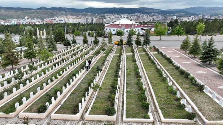 Sivas'taki bir mezarlıkta düzenli sıralanmış mezar taşları ve yeşil alanlar görünmektedir.