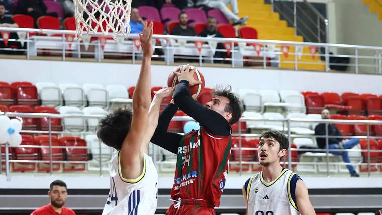 Bir basketbolcu, potaya atış yaparken rakip oyuncu tarafından savunuluyor.