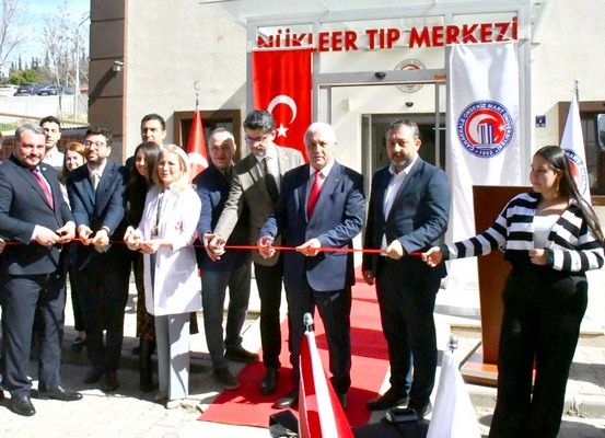 Nükleer Tıp Merkezi girişinde, aralarında beyaz önlüklü bir kişinin de bulunduğu grup kırmızı kurdele kesiyor.