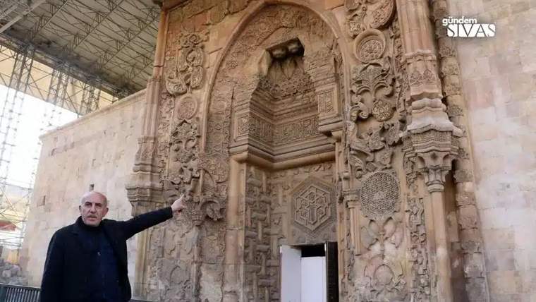 Bir kişi, Divriği Ulucami'nin taş işçiliğini gösteriyor.