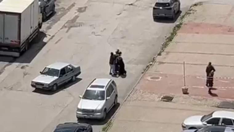 Bir grup insan, bir sokakta tartışıyor; çevrede birkaç araç var.