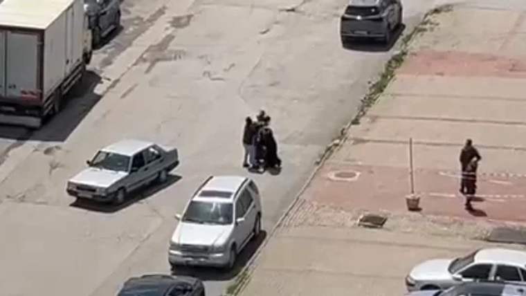 Bir grup insan, bir sokakta tartışıyor; çevrede birkaç araç var.