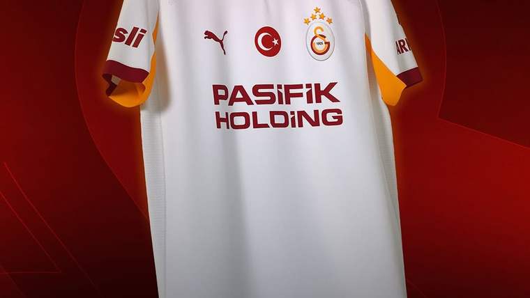 Kırmızı arka plan önünde Galatasaray armalı beyaz futbol forması; üzerinde Türk bayrağı ve sponsor yazısı görülüyor.