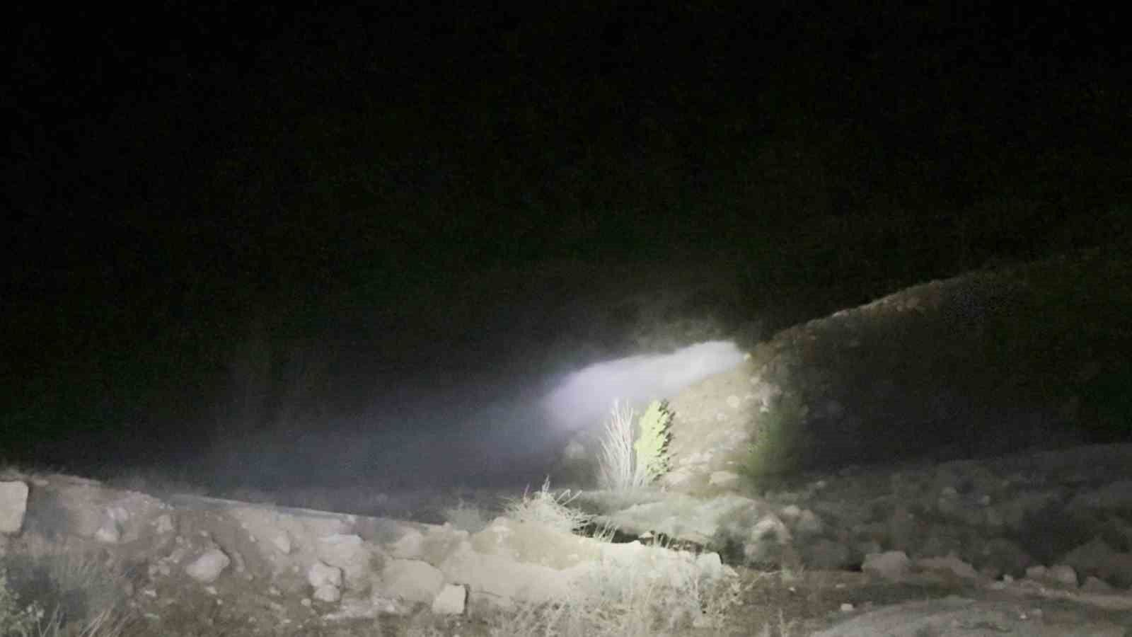 Gece karanlığında taşlı bir kanaldan taşan su, el feneri ışığında ilerliyor.