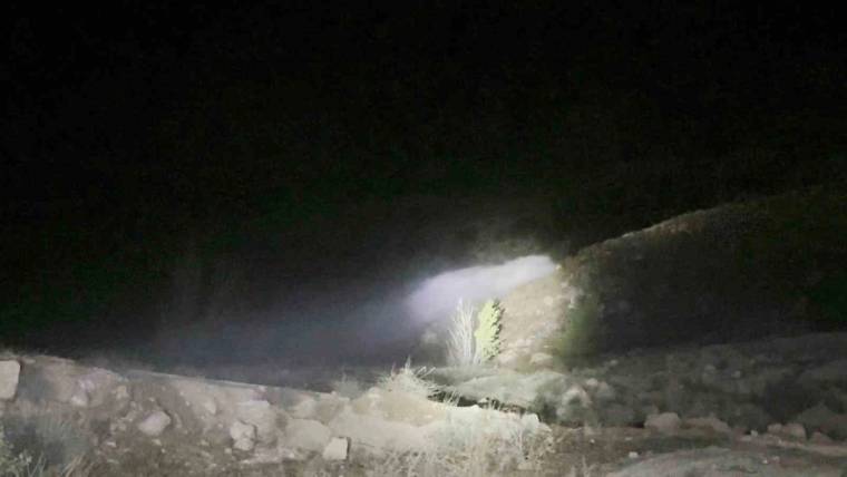 Gece karanlığında taşlı bir kanaldan taşan su, el feneri ışığında ilerliyor.
