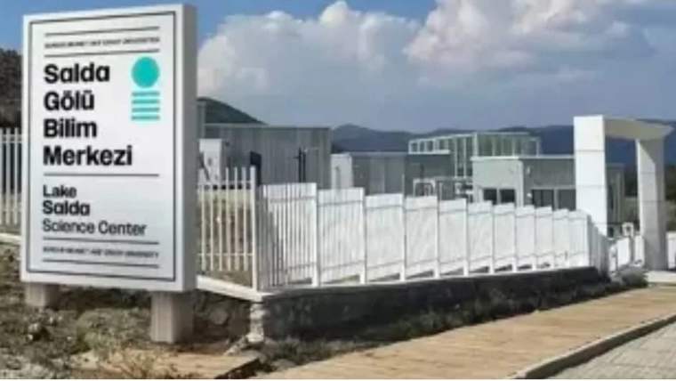 Üzerinde “Salda Gölü Bilim Merkezi” yazan tabela, çitlerle çevrili modern merkezin önünde duruyor.