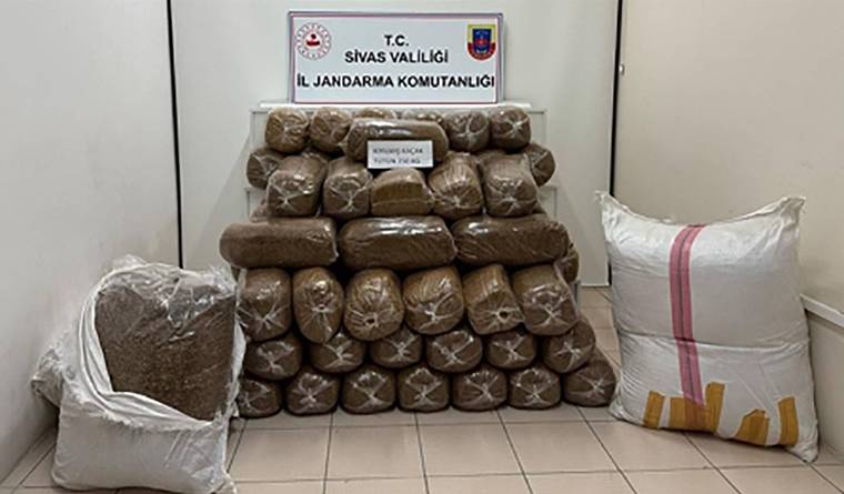 Üzerinde Sivas Valiliği İl Jandarma Komutanlığı yazan tabelanın önünde, paketlenmiş tütün balyaları ve çuvallar duruyor.