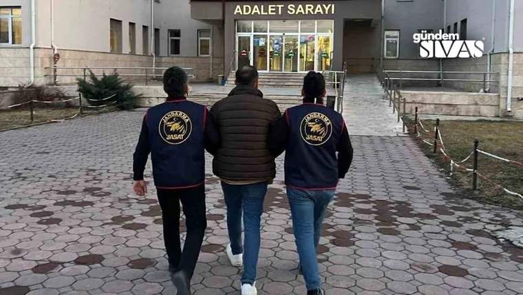 İki görevli, bir kişiyi adalet sarayına doğru götürüyor.