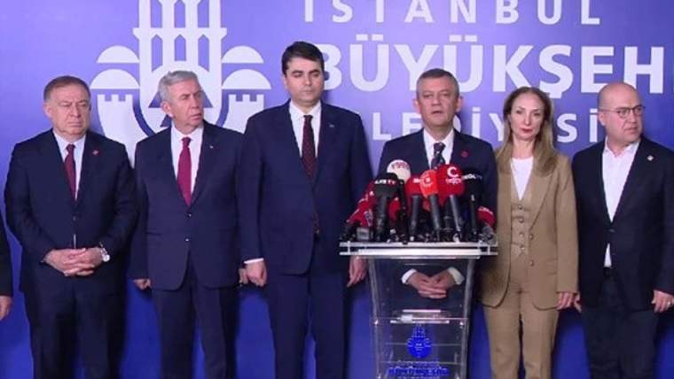 Mikrofonlarla donatılmış kürsünün çevresinde altı kişi duruyor; arkada İstanbul Büyükşehir Belediyesi yazısı görülüyor.