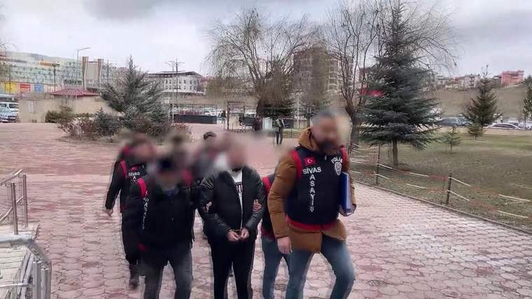 Polis ekipleri, gözaltındaki kişileri bir alandan çıkararak götürüyor.