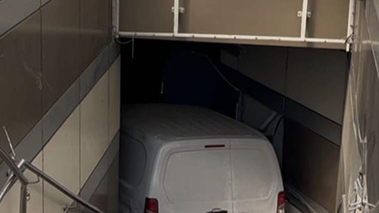 Beyaz bir otomobil, metro istasyonunun girişine girmiş ve kapının iç kısmında sıkışmış.
