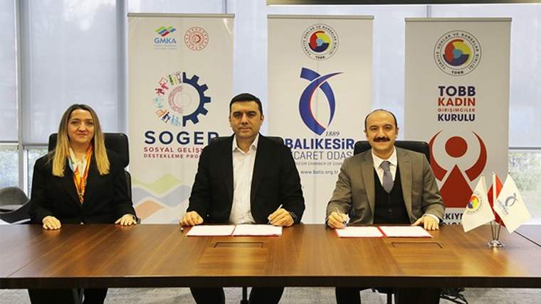 Masada oturan üç kişi, arkalarında SOGEP ve kadın kurulu logolarının bulunduğu afişlerle görülüyor.