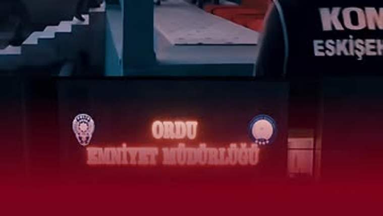 Üzerinde “KON ESKİŞEHİR” yazılı yelek giyen kişi, bir bina girişinin önünde görülüyor.