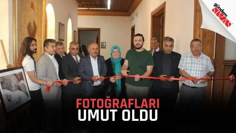 İç mekânda bir grup kişi, ellerindeki makaslarla kırmızı kurdeleyi keserken yan yana duruyor.