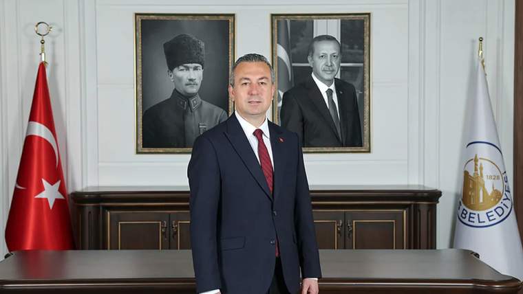 Bir kişi, arkasında Atatürk ve Erdoğan'ın portrelerinin bulunduğu bir odada duruyor.