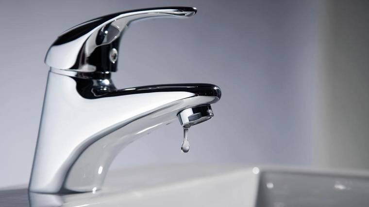 Krom renkli bir lavabo musluğunun ucunda tek bir su damlası görülüyor.