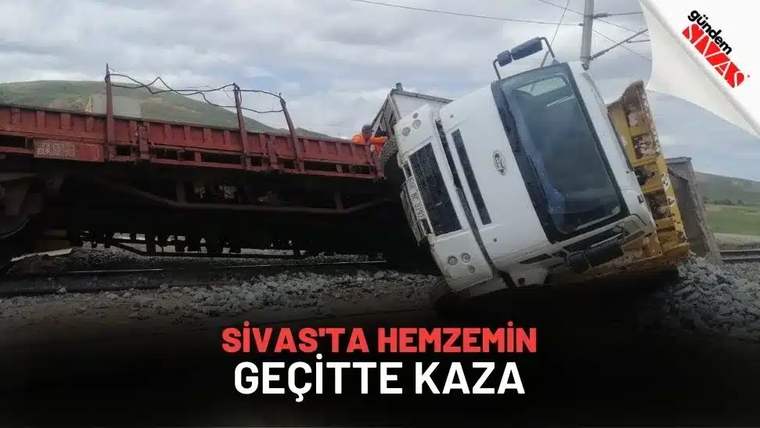 Demiryolu geçidinde devrilmiş bir kamyon, rayların yanında duruyor.