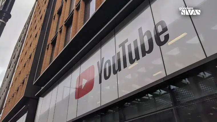 Bir binanın cam cephesinde kırmızı YouTube logosu ve büyük YouTube yazısı görülüyor.