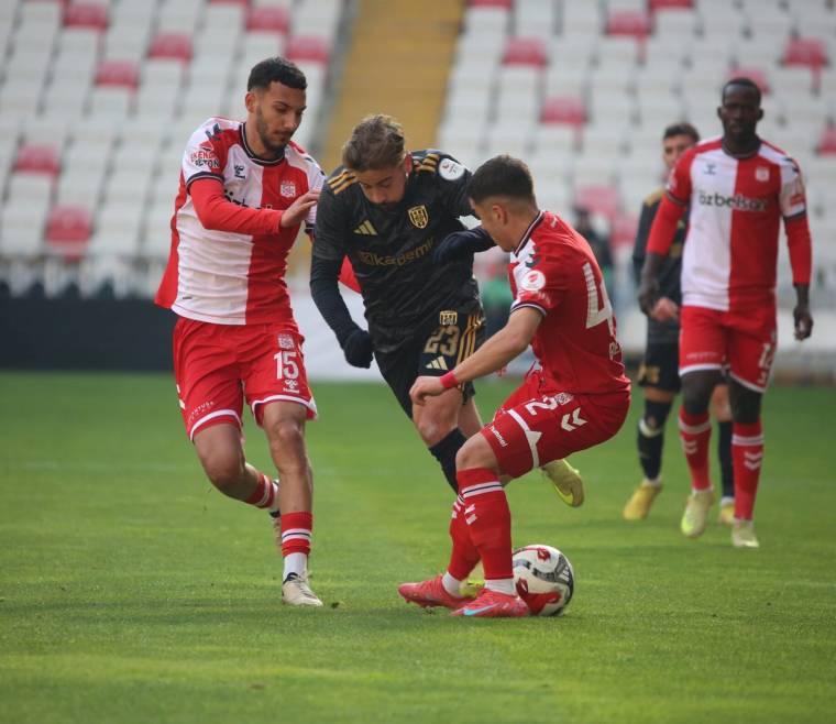 Futbol sahasında kırmızı formalı iki oyuncu, siyah formalı rakipleriyle top mücadelesi yapıyor.