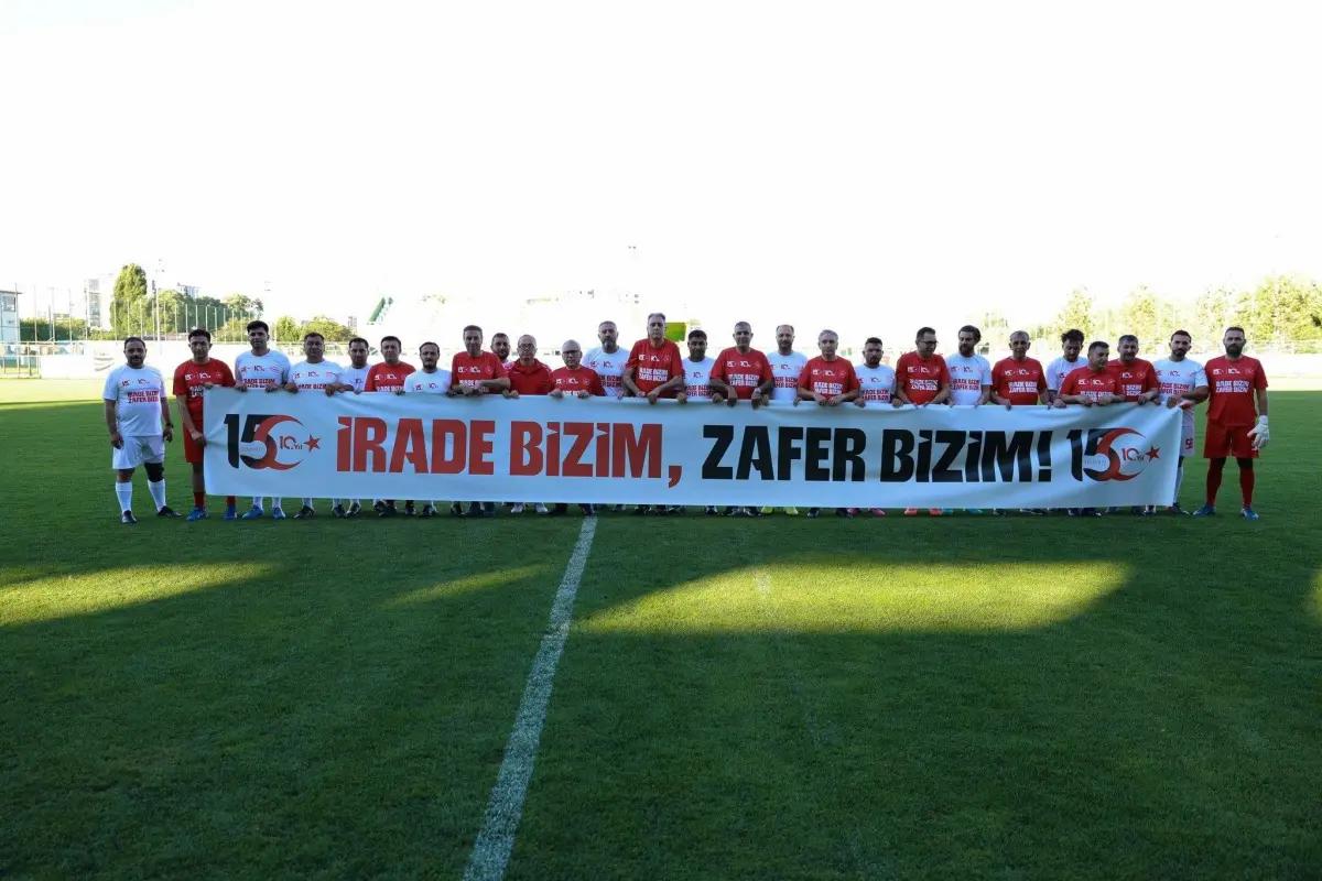 Futbol sahasında yan yana duran oyuncular, üzerinde “İrade bizim, zafer bizim!” yazılı pankartı tutuyor.