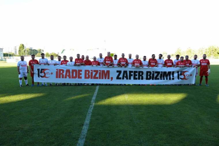 Futbol sahasında yan yana duran oyuncular, üzerinde “İrade bizim, zafer bizim!” yazılı pankartı tutuyor.