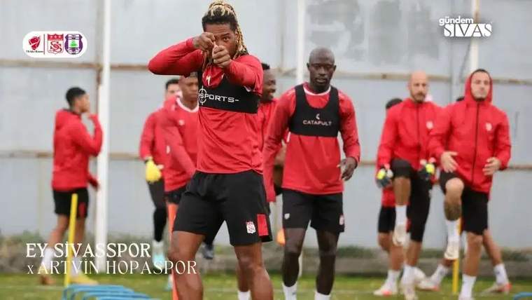 Antrenman yapan futbolcular, Sivaspor forması giymiş, bir oyuncu kameraya doğru parmakla işaret ediyor.