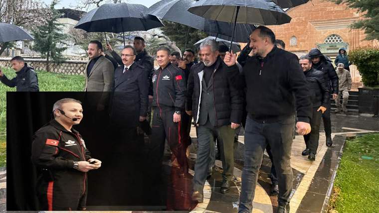 Yağmurlu bir günde, şemsiyelerle yürüyen kalabalık bir grup, bir etkinlik alanına doğru ilerliyor.