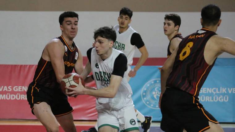 Basketbol sahasında iki takım oyuncuları, top için mücadele ediyor. Arka planda diğer oyuncular yer alıyor.