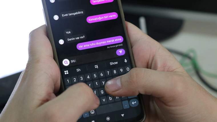Bir kişinin akıllı telefonunda mesajlaşma uygulaması açık, parmakları klavyede yazı yazıyor.