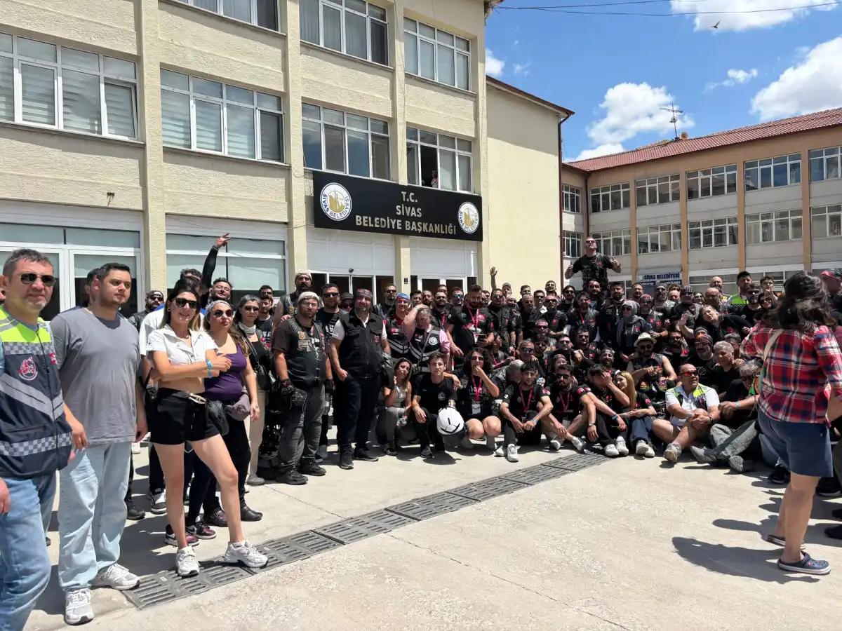 Sivas Belediyesi binası önünde, motosiklet kıyafetleri giyen kalabalık bir grup toplu halde duruyor.