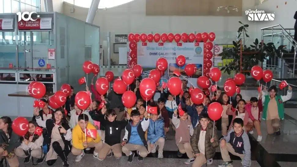 Türk bayrağı desenli balonlar tutan çocuklar, havalimanında bir araya gelmiş.