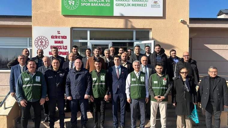Bir grup insan, Gençlik Merkezi önünde toplu halde poz veriyor.
