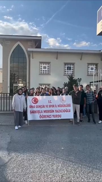 Bir grup genç, üzerinde Sivas Gençlik ve Spor Müdürlüğü ile öğrenci yurdu yazan pankartı tutuyor.