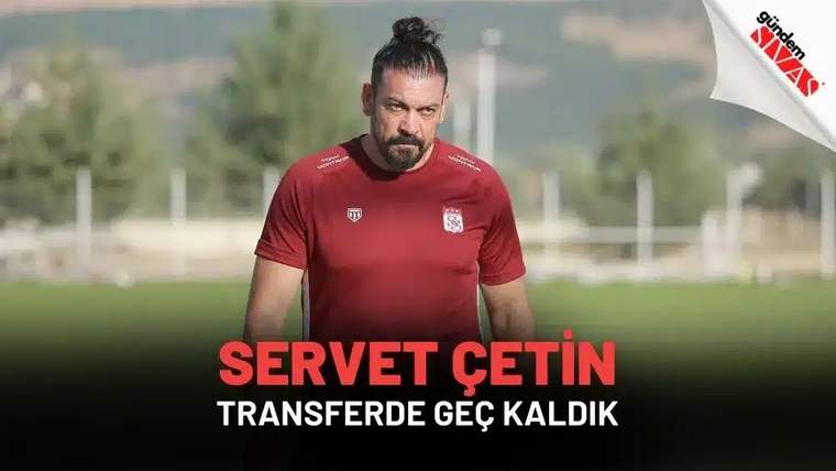 Kırmızı antrenman forması giymiş bir futbolcu, antrenman sahasında yürürken görünüyor.