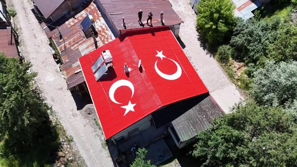 Bir binanın çatısında büyük Türk bayrağı ve ay yıldız figürleri yer alıyor.