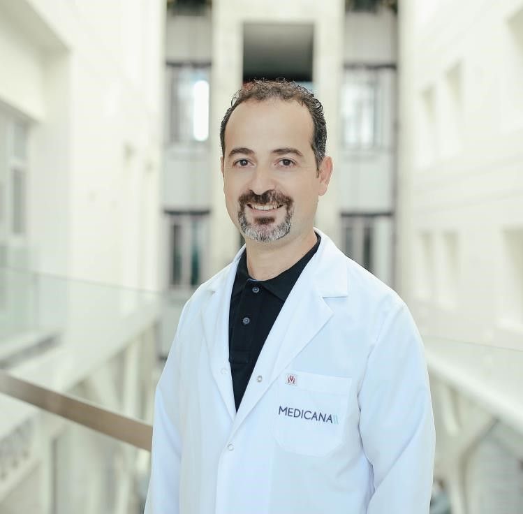 Beyaz lab coat giymiş bir doktor, iç mekan bir hastanede gülümsüyor.