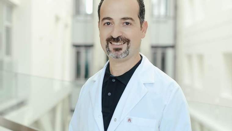 Beyaz lab coat giymiş bir doktor, iç mekan bir hastanede gülümsüyor.