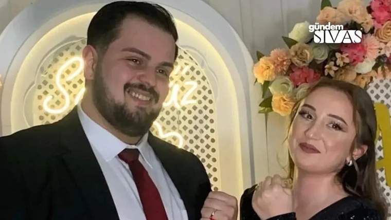 Düğün salonunda poz veren bir çift, arka planda çiçekler ve dekoratif bir arka plan var.