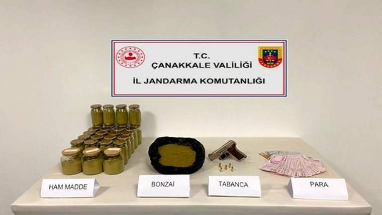 Çanakkale İl Jandarma Komutanlığı tabelası önünde ham madde, bonzai, tabanca ve para sergileniyor.