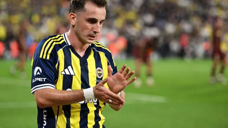 Sarı-lacivert çubuklu forma giyen futbolcu, sahada ellerini birbirine vururken görülüyor.