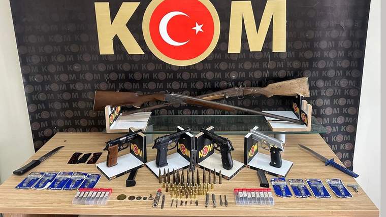 Bir masa üzerinde çeşitli ruhsatsız silahlar, mermiler ve tarihi eserler sergileniyor.