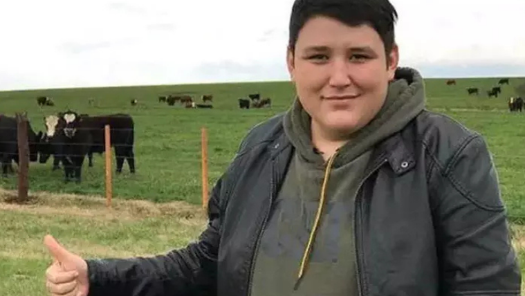 Yeşil bir alanda, ineklerin bulunduğu bir çiftlikte, gülümseyen bir kişi parmaklarıyla onay işareti yapıyor.