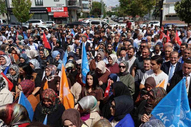 Sokakta toplanan kalabalık arasında farklı renklerde bayraklar taşınıyor; arka planda “Eczane” tabelası görülüyor.