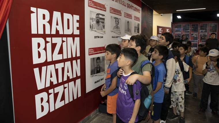 Bir grup çocuk, 15 Temmuz Anı Merkezi'nde sergilenen panoya dikkatle bakıyor.