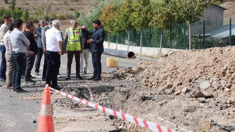 Bir grup insan, yol kenarında açık bir kazı alanında toplanmış, tartışıyorlar.