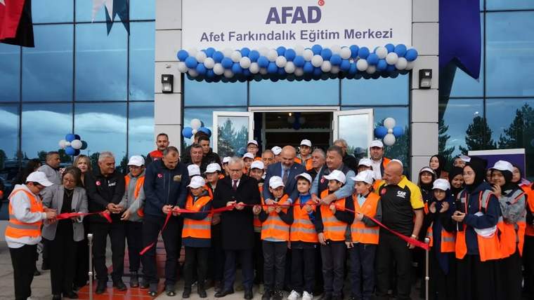 Afet Farkındalık Eğitim Merkezi'nin açılışında kurdele kesen kalabalık, turuncu yelek giymiş kişilerle birlikte poz veriyor.